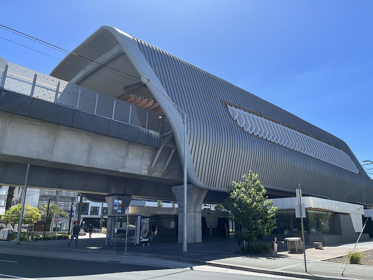 Carnegie railway station's curved grey roof and bus stop seen from Koornang Road, Carnegie