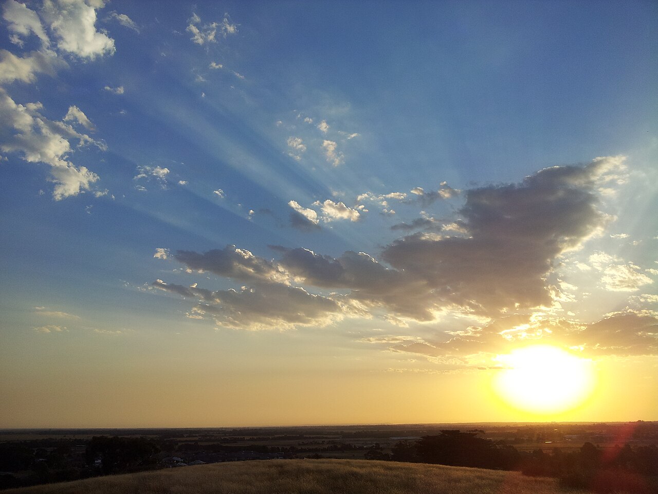 Sun setting beneath streaks of cloud