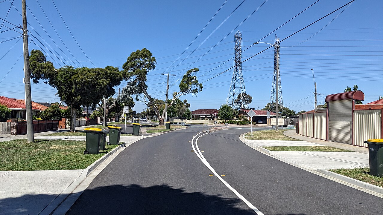 Curving suburban road in Lalor with high-voltage power lines