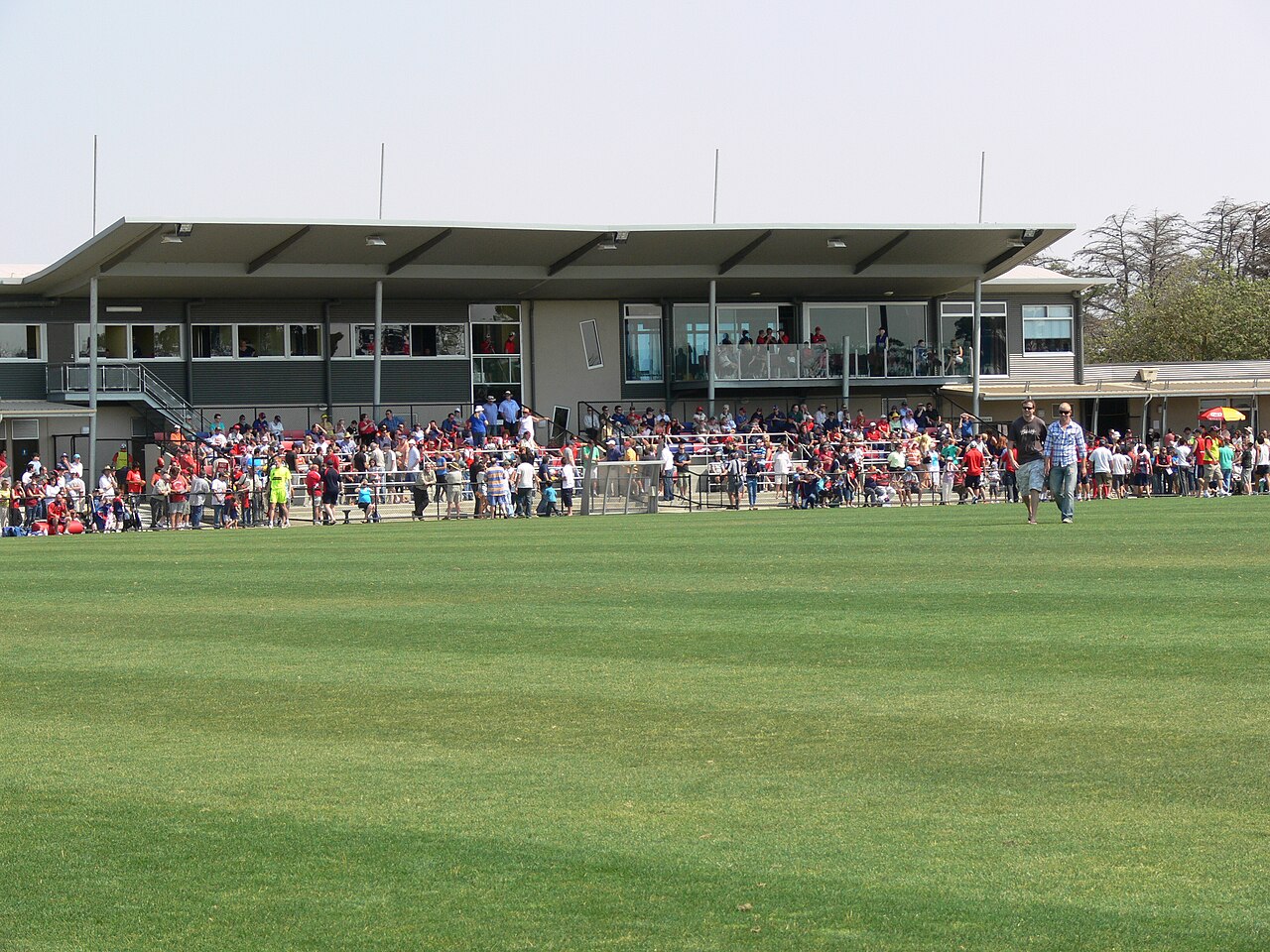 Spectators lining a football pitch in front of a pavilion