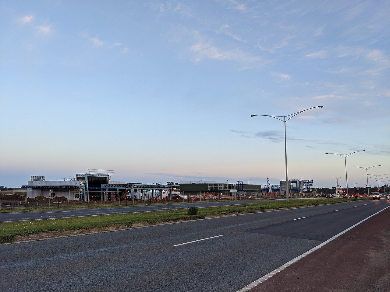 Wide road at dusk past new fast food stores under construction