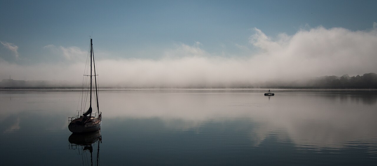 Yacht moored on still water in morning mist
