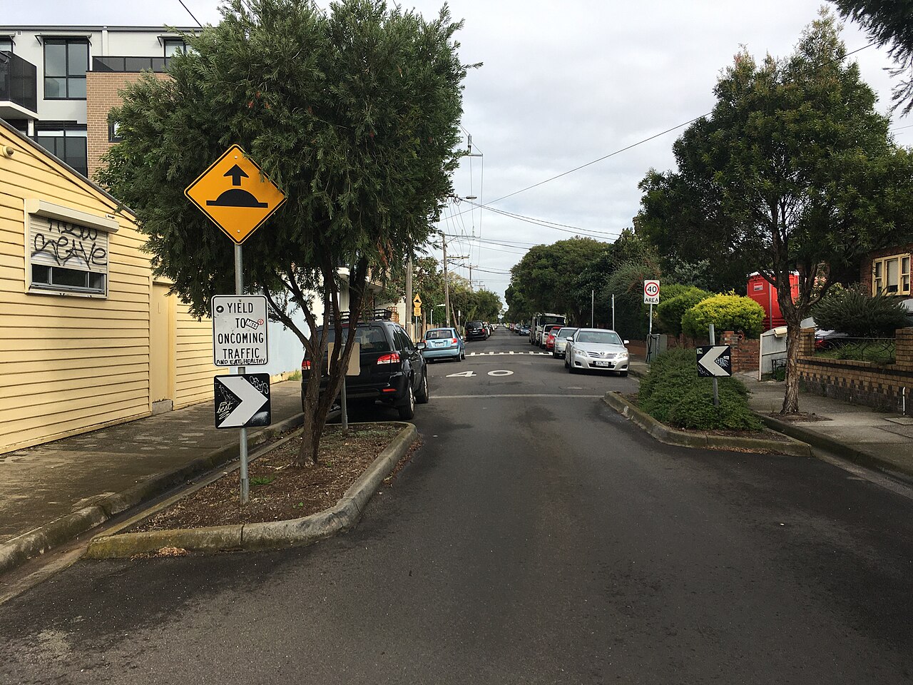Quiet residential street with speed humps, trees and parked cars