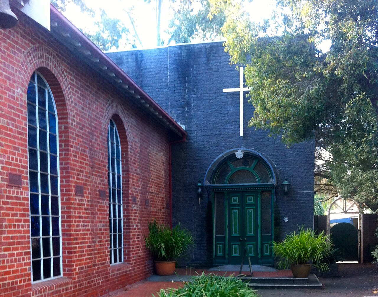 Arched entrance and red-brick wall of St James the Great church