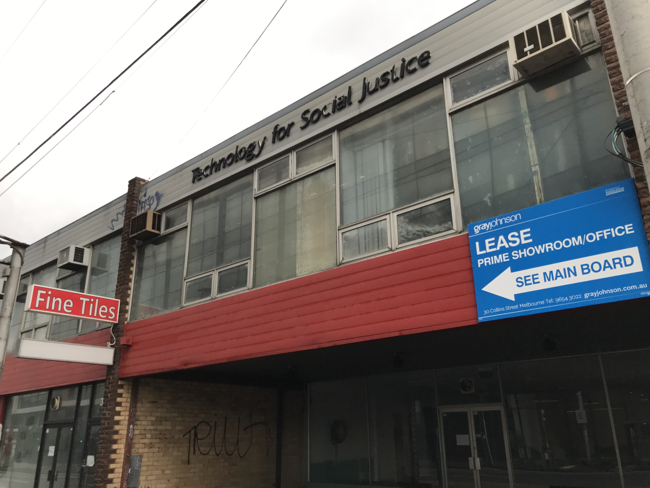 Two-storey shopfront building with a red awning and a lease sign