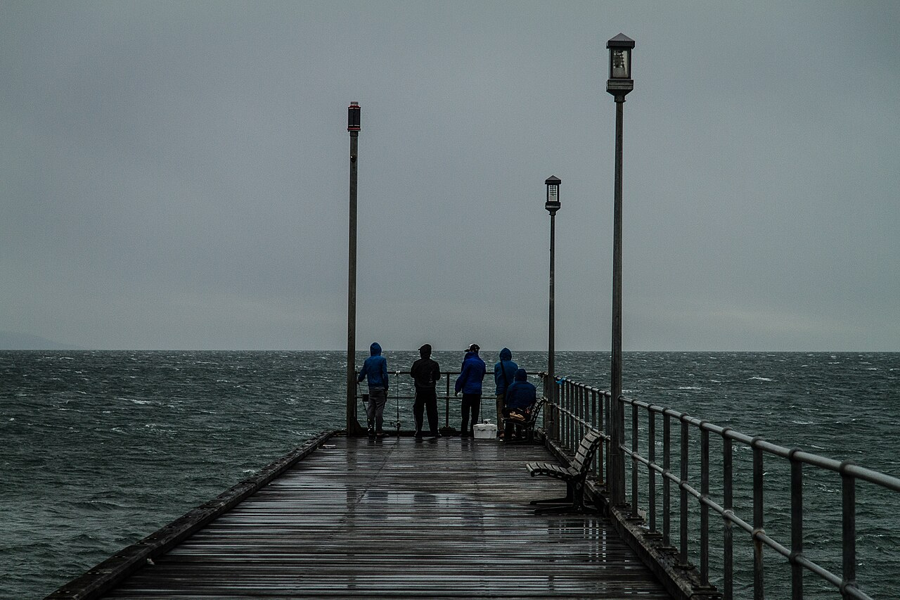 Small figures on a pier under a stormy grey sky