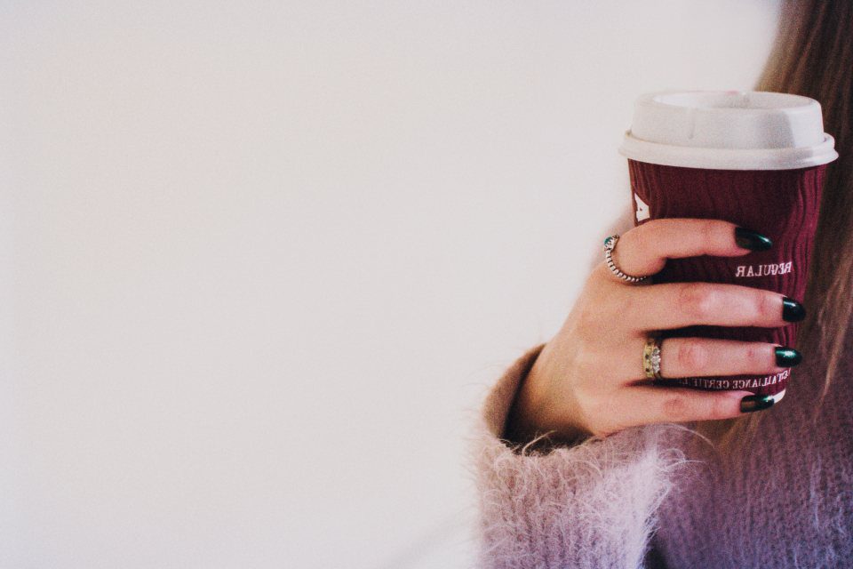 A takeaway coffee cup held in one hand